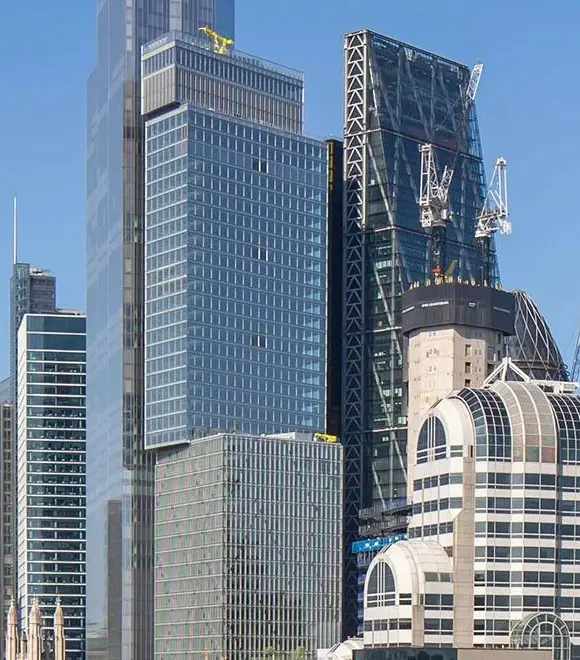 Modern skyscrapers with cranes against blue sky.