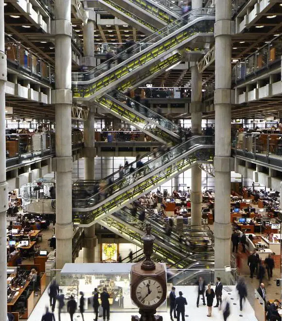 Modern office atrium with escalators and clock.