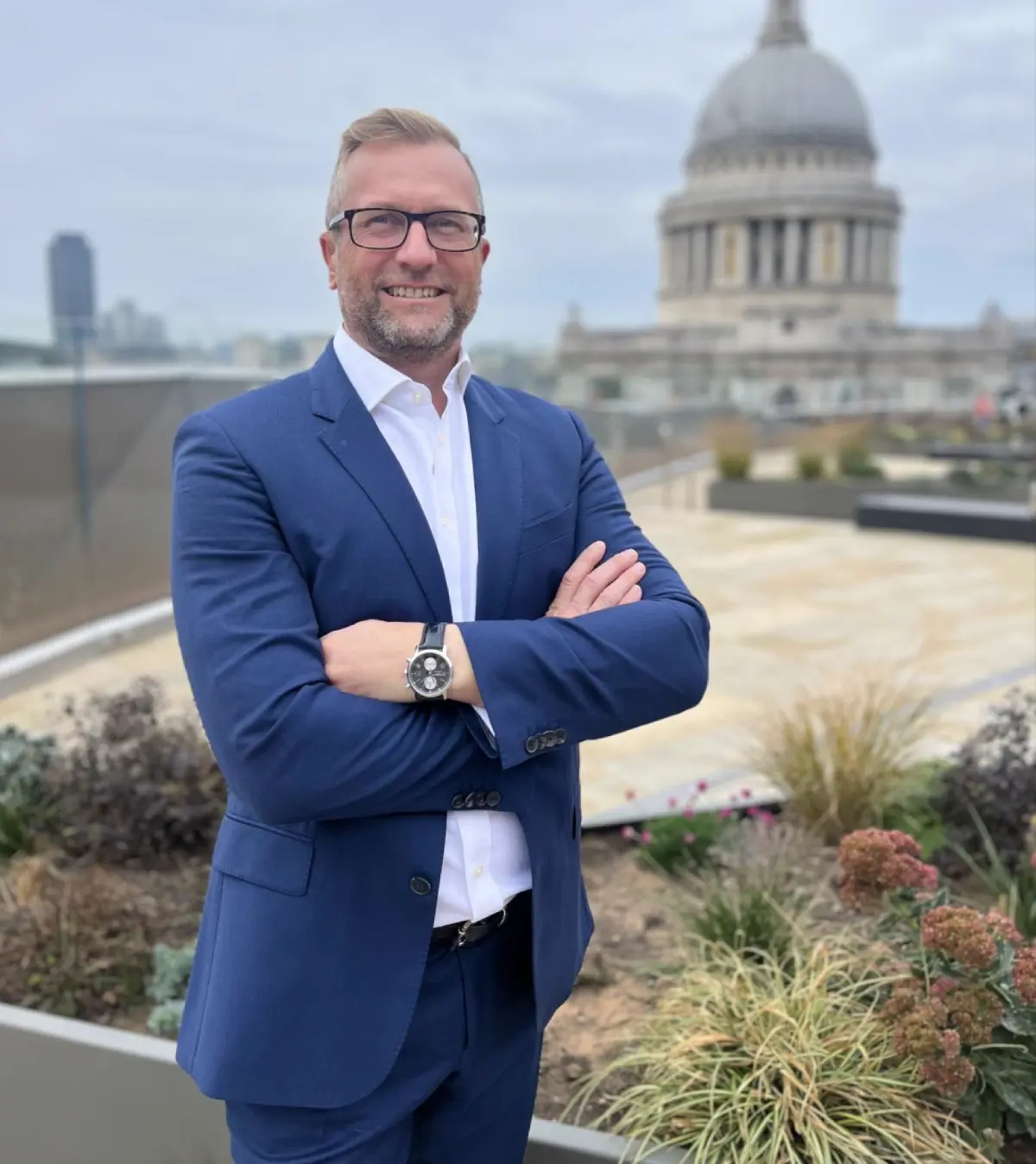 Man in blue suit, rooftop city view.