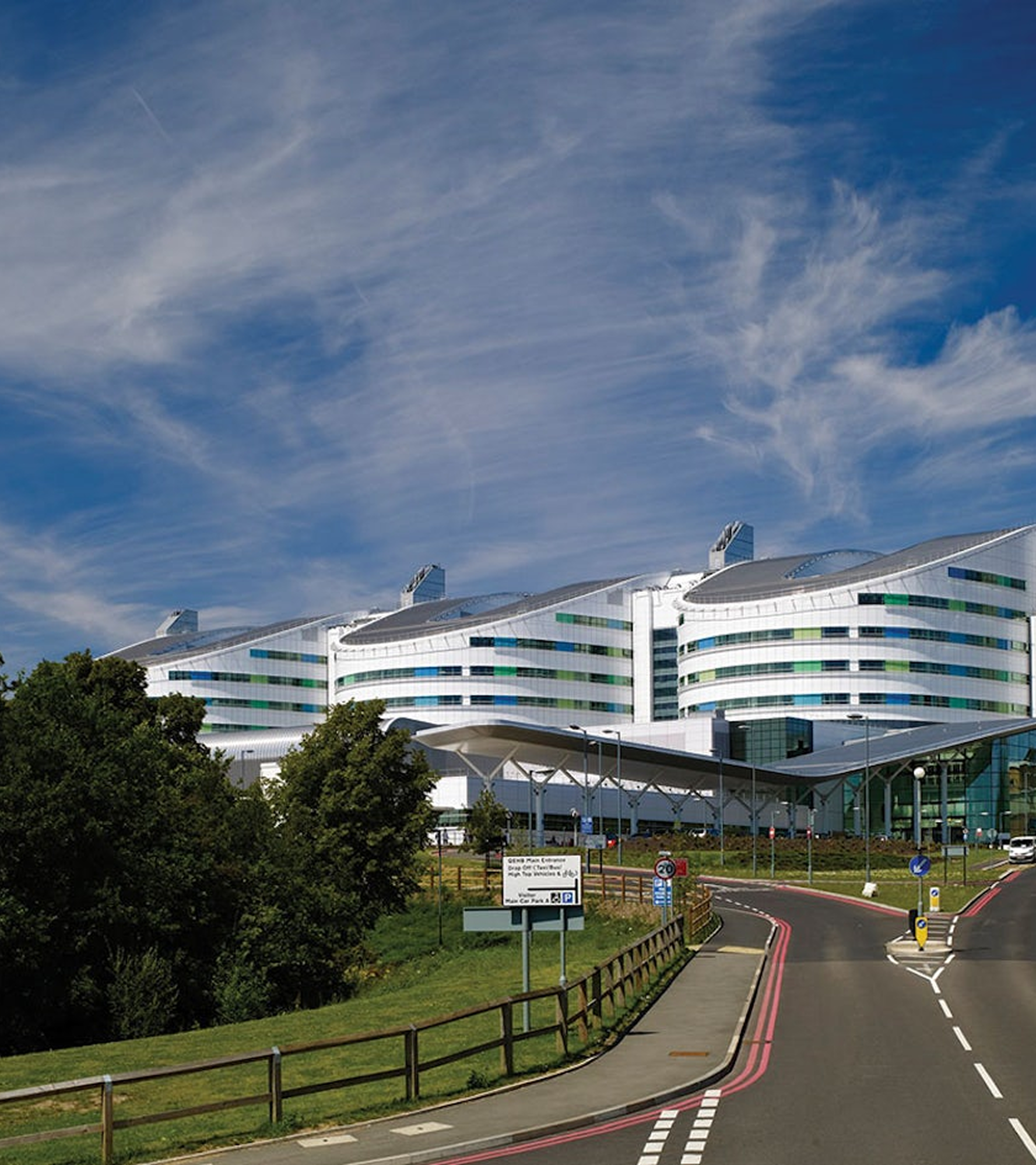 Modern hospital building with curved architecture under a blue sky.