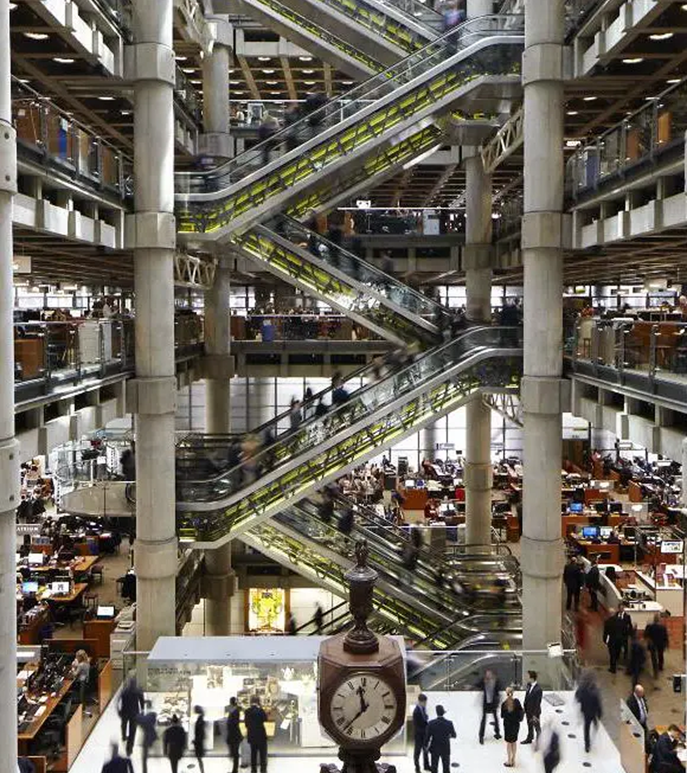 Modern office atrium with escalators and clock.