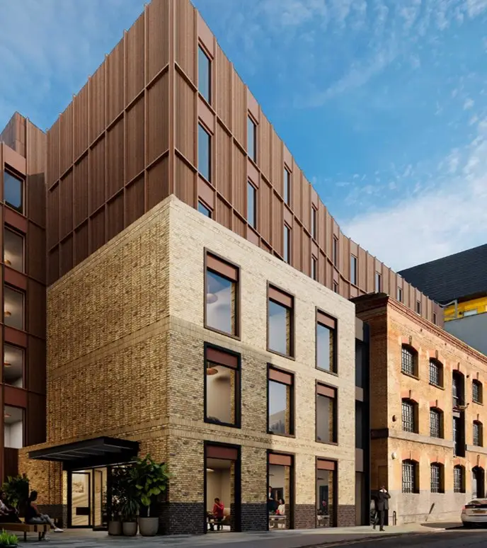 Modern building combining brick and metal facade under a blue sky.