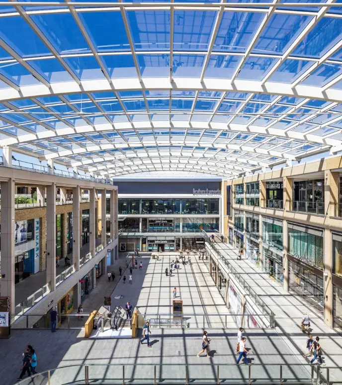 Modern shopping mall atrium with glass ceiling and open space.