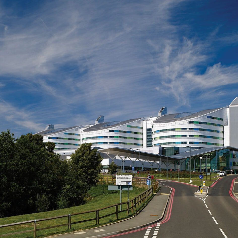 Modern white hospital building under a blue sky.